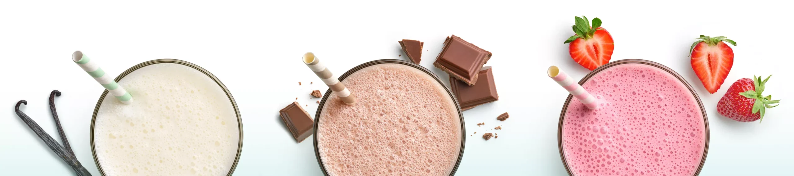 Overhead view of glasses containing Vanilla, Chocolate and Strawberry Protein+ beverages, garnished